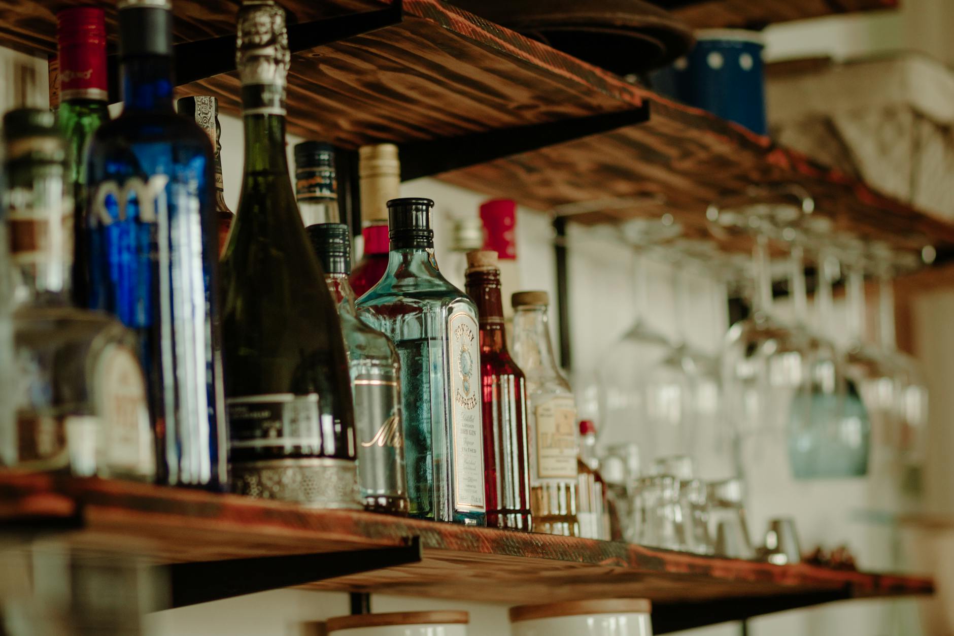 Butelki różnych alkoholi ustawione na rustykalnej drewnianej półce Butelki różnych alkoholi ustawione na rustykalnej drewnianej półce