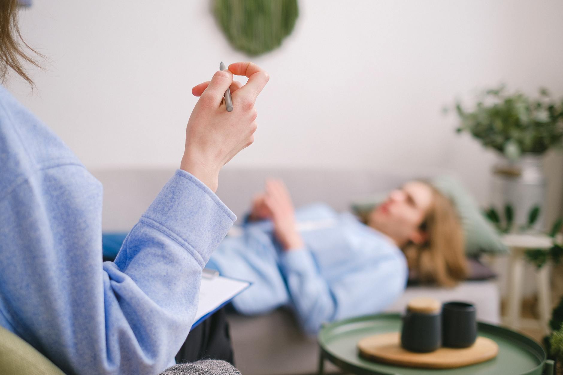 Psycholog robi notatki, pacjent leży spokojnie na kanapie podczas terapii