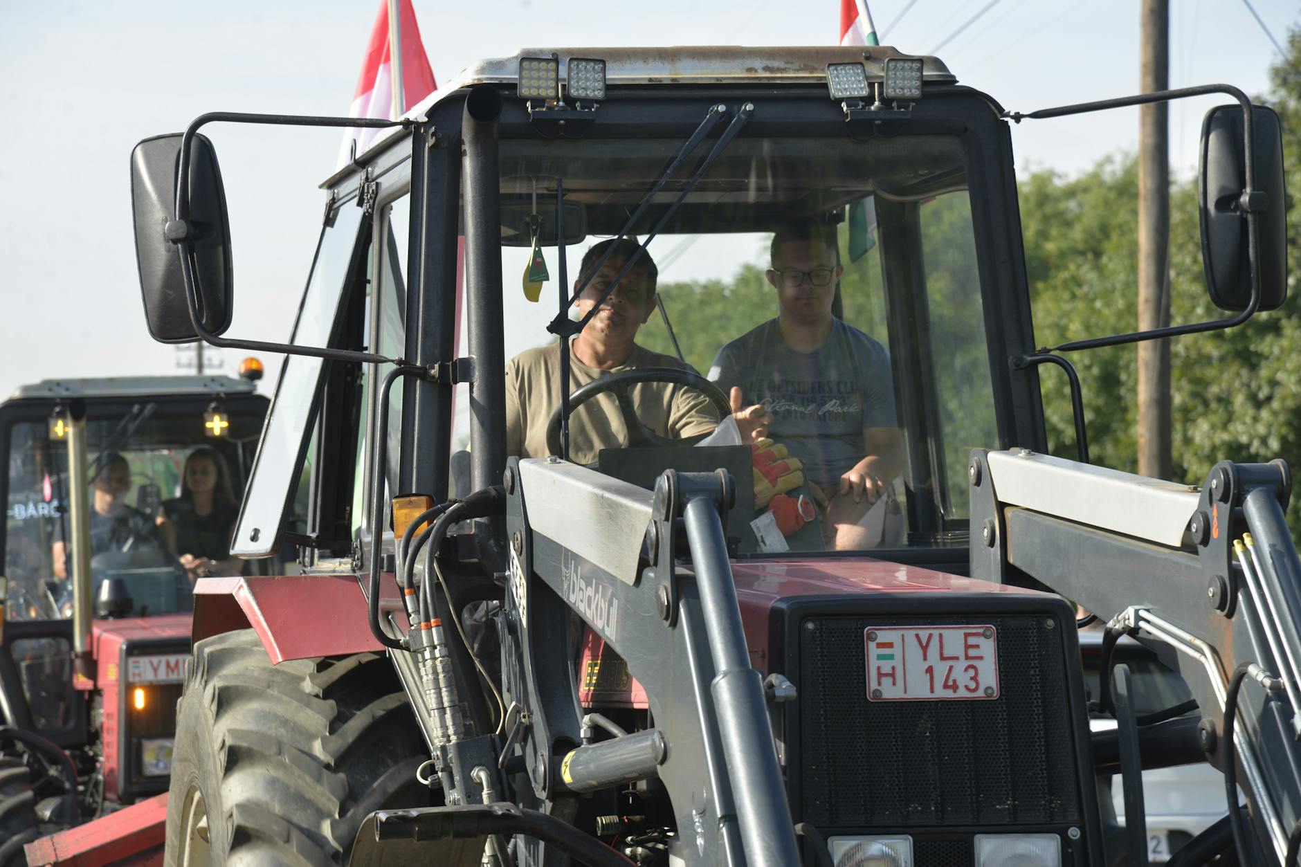 Rolnicy prowadzą ciągniki na polu w słoneczny dzień