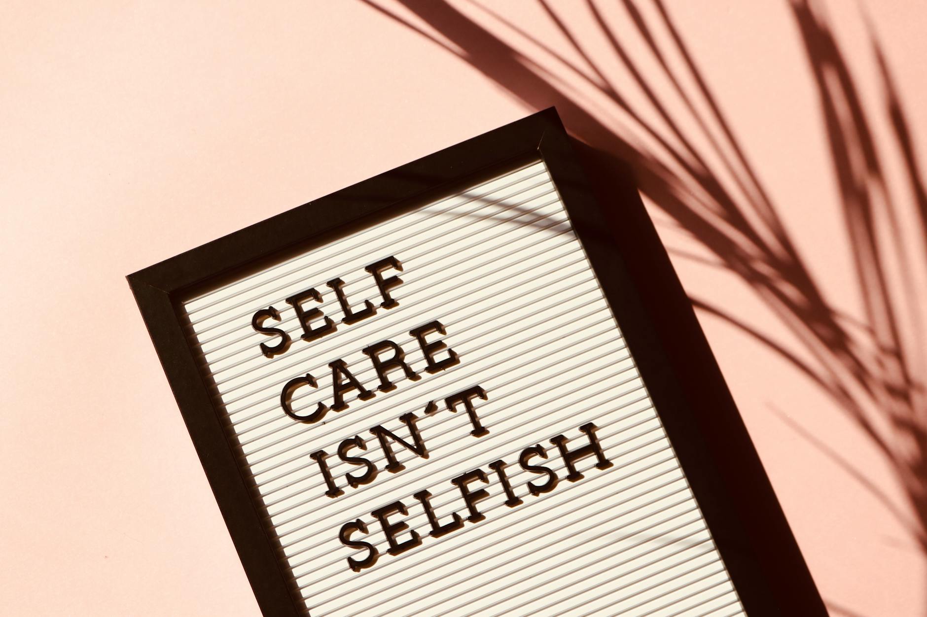 Tablica z napisem Self care isn’t selfish na różowym tle