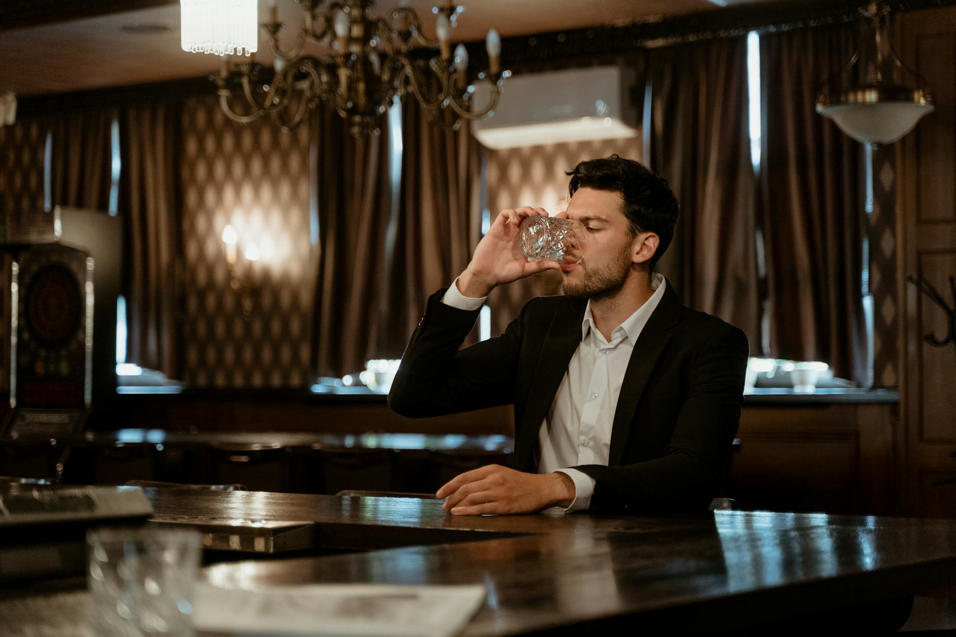 Mężczyzna w garniturze pije alkohol przy eleganckim barze