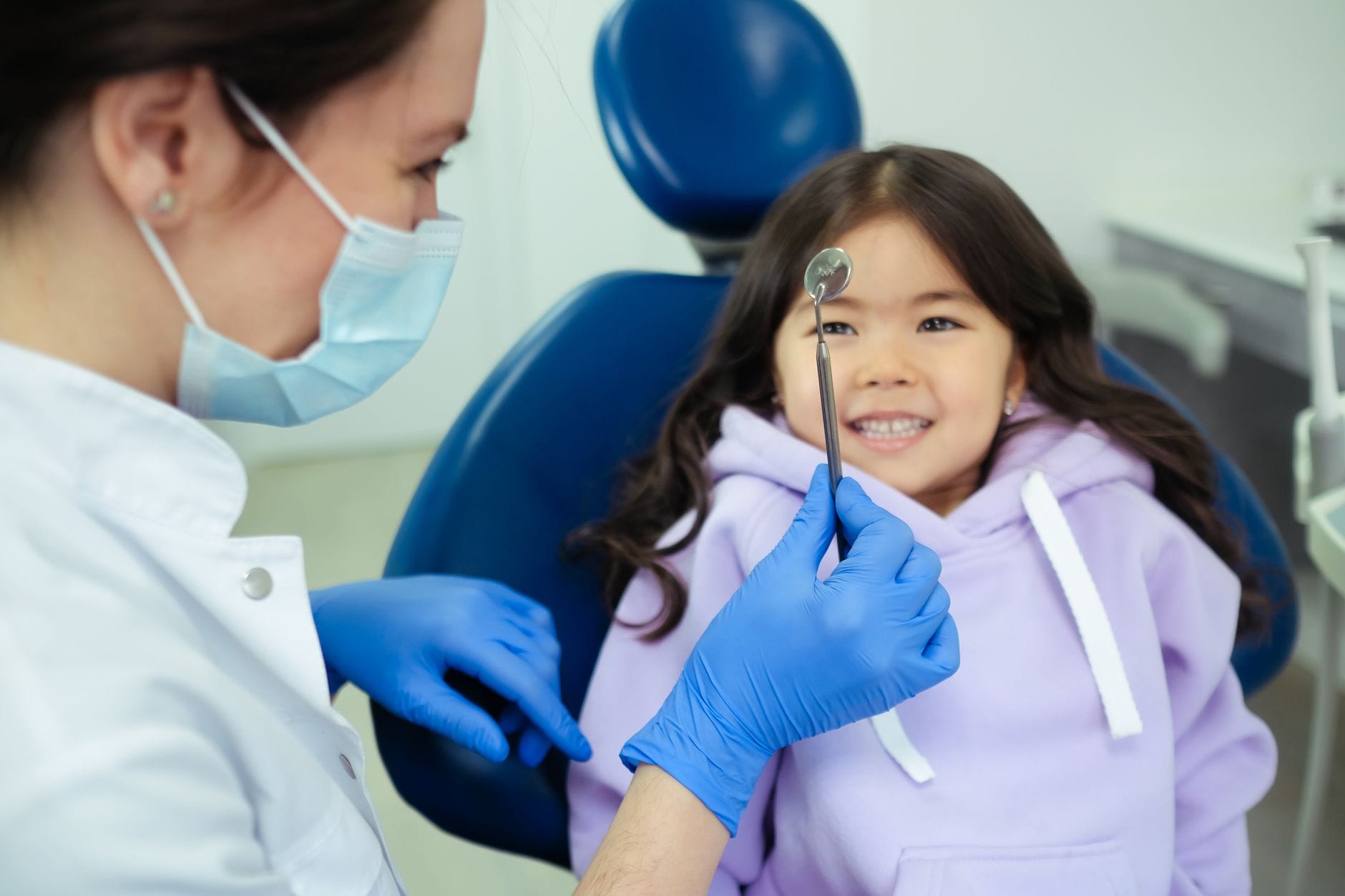 Dentysta bada uśmiechnięte dziecko w przyjaznym gabinecie