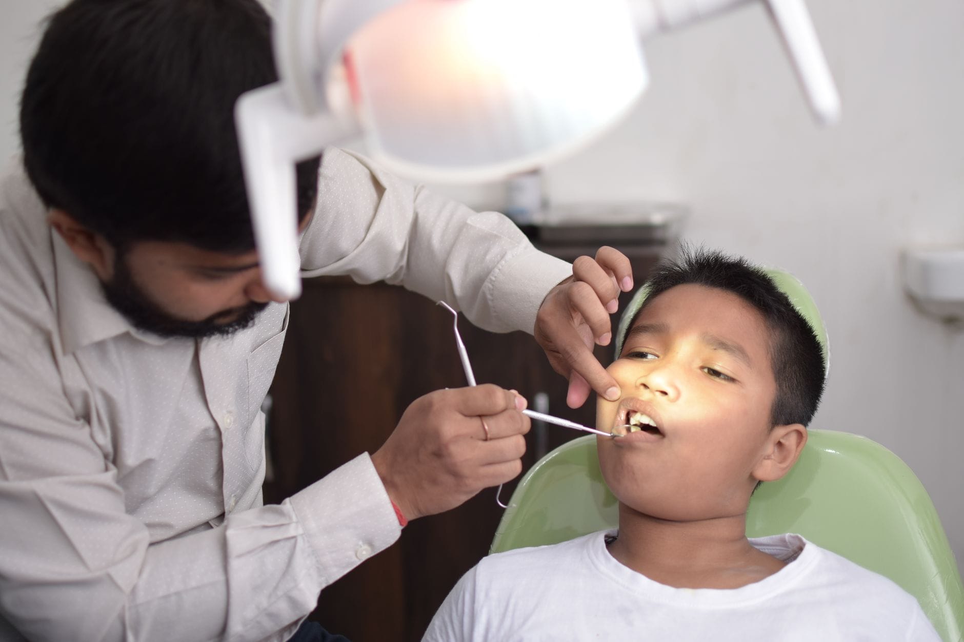 Dentysta zagląda do buzi dziecka w jasnym gabinecie stomatologicznym